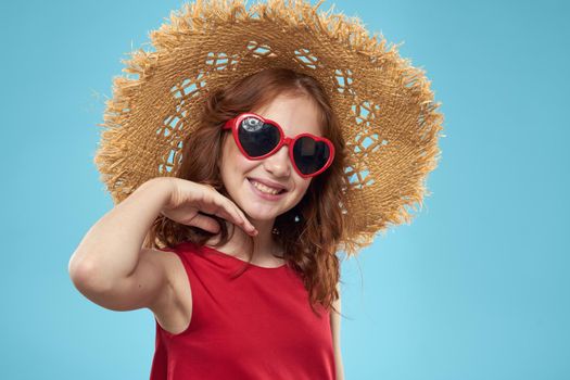 Girl in a beach Straw hat in sunglasses curly hair fun blue background. High quality photo
