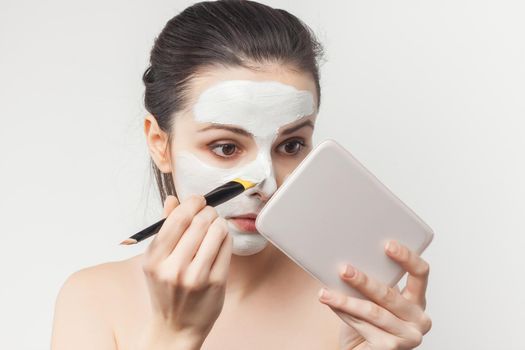 woman with bare shoulders with a brush in her hands applying makeup. High quality photo