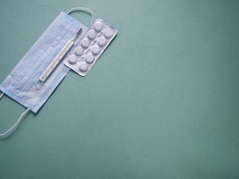 Tablets in blister packaging, body thermometer and personal protective equipment. close-up.