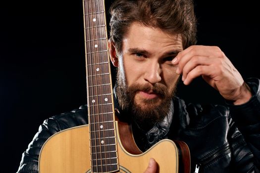 A man with a guitar in his hands leather jacket music performance rock star modern style dark background. High quality photo