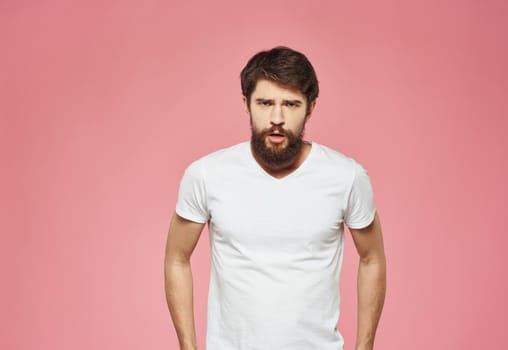 Man on a pink background in a white t-shirt emotions model cropped view. High quality photo
