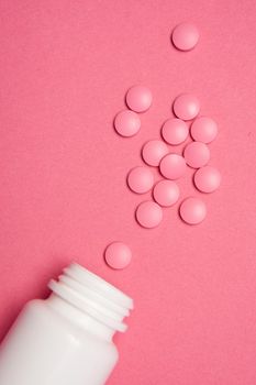 Open jar with pills on pink background coldspace top view. High quality photo