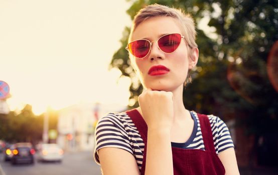 fashionable woman with short hair in glasses and a sundress walks down the street in summer. High quality photo