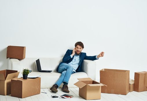 a man sitting on the couch talking on the phone an official box of things. High quality photo