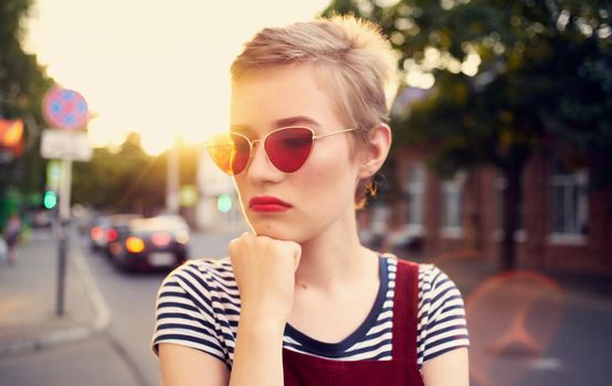 fashionable woman with short hair in glasses and a sundress walks down the street in summer. High quality photo