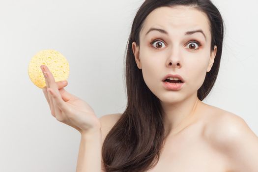 brunette with bare shoulders sponge in hand grooming. High quality photo