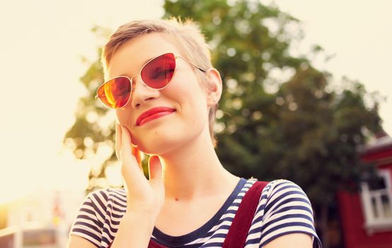 romantic woman in a sundress and red glasses walks along the city street in summer. High quality photo