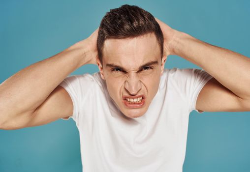Angry man in white t-shirt gesture with hands displeasure blue background. High quality photo