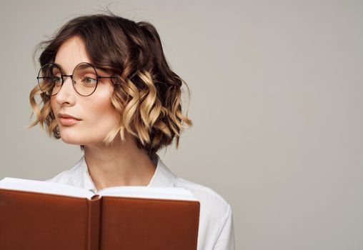 Business woman with open notebook in her hands and glasses on her face, white shirt. High quality photo