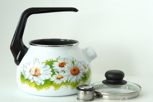 The kettle is white enamelled with a whistle and a pattern. High quality photo