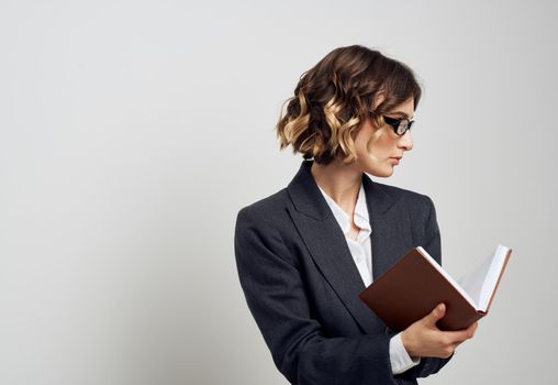 Business woman in a classic suit with a book in her hands on a light background indoors. High quality photo