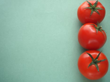 Ripe vegetables, three red tomatoes on a green background, close-up.