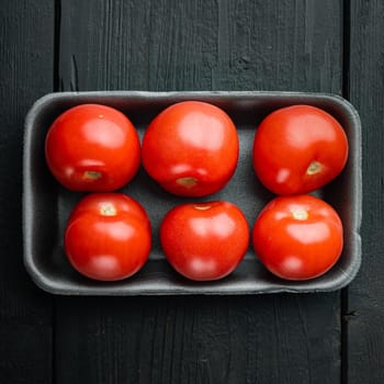 Fresh red organic tomatoes, on black wooden table