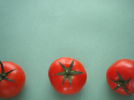 Ripe vegetables, three red tomatoes on a green background, close-up.