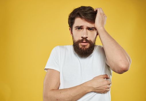 Sad men on yellow background portrait cropped view of white t-shirt. High quality photo