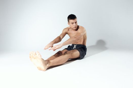 man doing sports exercises while sitting on the floor indoors. High quality photo