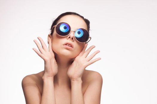 woman wearing sunglasses naked shoulders charm fashion light background. High quality photo