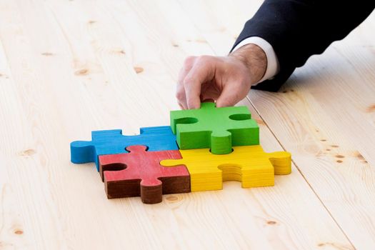 Business man assembling four color jigsaw puzzle pieces problem solution ideas concept