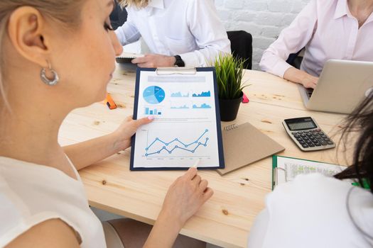 Diverse executive business people team discussing work results at meeting, multiracial businessmen talking analyzing financial statistics report sitting together in modern office