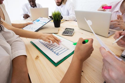 Diverse executive business people team discussing work results at meeting, multiracial businessmen talking analyzing financial statistics report sitting together in modern office