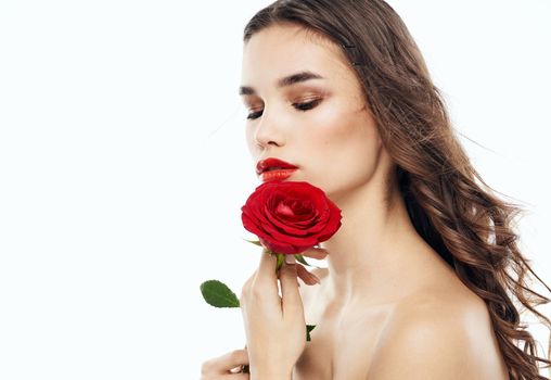 Charming brunette woman with bare shoulders and a fragrant flower near her face. High quality photo