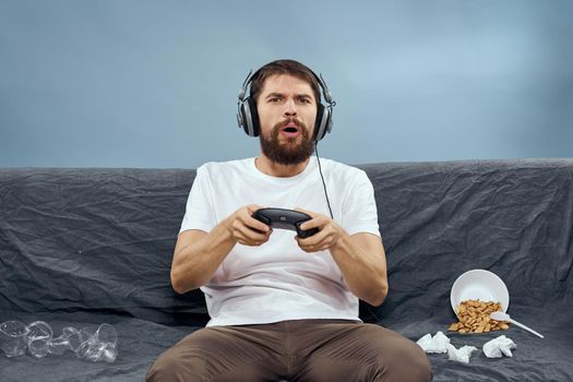 cheerful man sitting on the couch playing entertainment technology. High quality photo