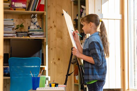 A ten-year-old girl draws on an easel at home