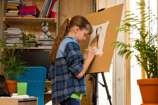 Girl draws a cat on an easel in her room at home