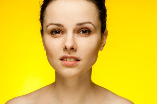 pretty woman naked shoulders smile clear skin yellow background. High quality photo