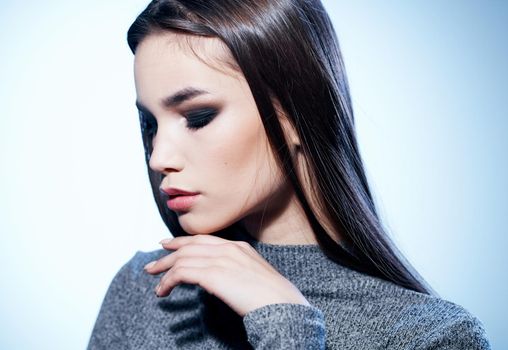Portrait of a beautiful brunette in a gray sweater and eye shadow, evening makeup. High quality photo