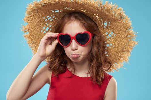 Cute little girl in a straw hat dark glasses close-up blue background. High quality photo