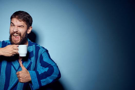 emotional man in pajamas morning lifestyle drink blue background. High quality photo