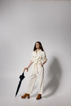 pretty woman in white suit holds hand in pocket umbrella in hands modern style. High quality photo