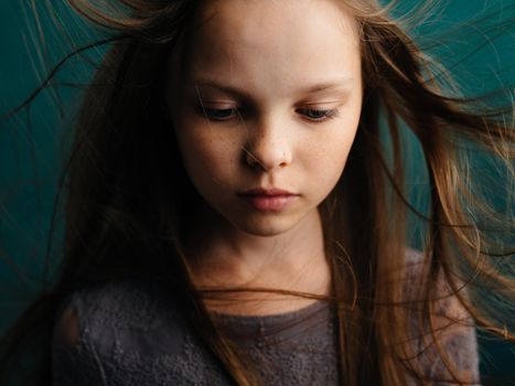 Cute little girl with tousled hair on a turquoise background beautiful face. High quality photo