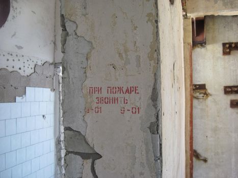 crumbling walls of the old building. Inscription - in case of fire call