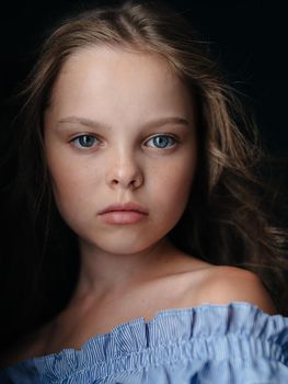 Portrait of a beautiful little girl on a dark background in a sundress, naked shoulders. High quality photo