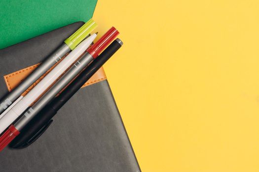 notepad markers pens office supplies and yellow green background. High quality photo