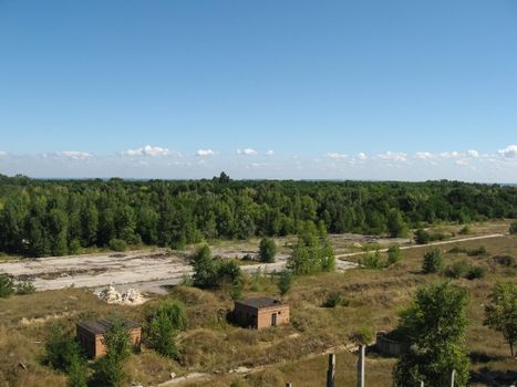 View from above on the site with old destroyed buildings, overgrown grass and trees.