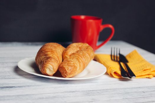 fresh croissant on a plate kitchen utensils coffee cup breakfast. High quality photo