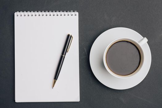 the dark background a Cup of coffee office Notepad handle the view from the top. High quality photo