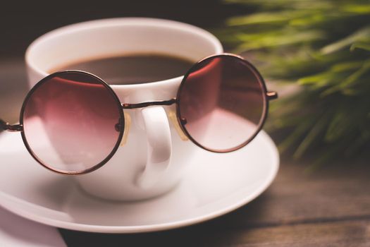 cup of coffee with glasses on a saucer and a wooden table flower in a pot in the background. High quality photo
