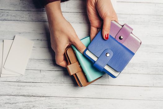 multicolored business card holders in female hands and a pack of white paper on a wooden background. High quality photo