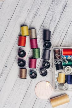 colored threads on a wooden background sewing accessories needles pins buttons. High quality photo