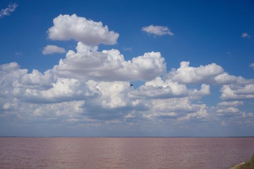 landscape overlooking a pink salt lake under a blue sky with clouds, natural beauty