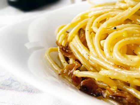 detail of spaghetti carbonara served in a white dish. Italian food. Famous typical Roman recipe. Close-up view of cooked spaghetti