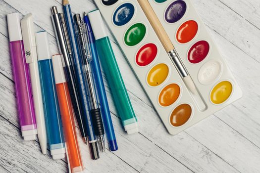 watercolor paints colored pencils and markers on wooden table top view. High quality photo