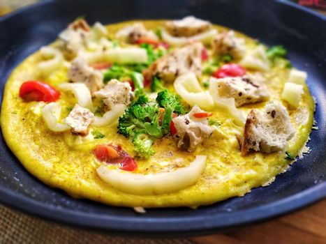omelet with vegetables and crunches in a frying pan