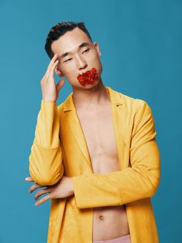 A man in a yellow jacket on a naked body and a red flower in his mouth. High quality photo