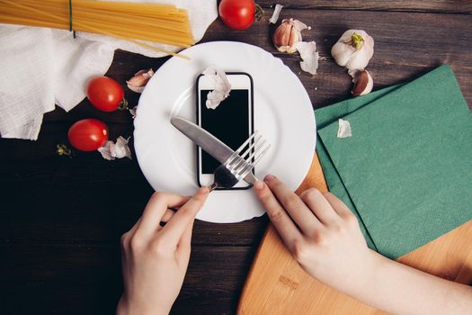 phone in a plate slicing with a knife eating wooden table. High quality photo
