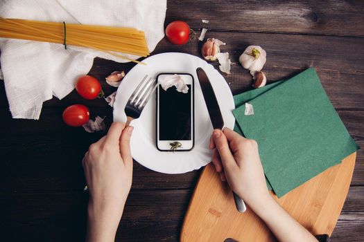 phone in a plate slicing with a knife eating wooden table. High quality photo
